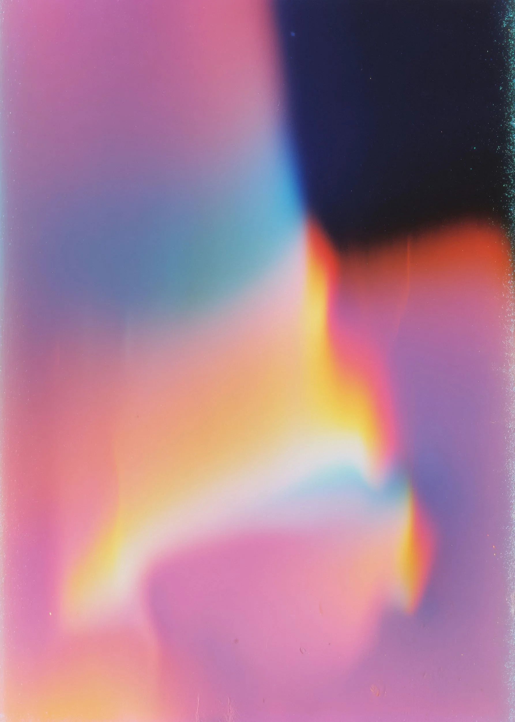 Abstract colorful background with gradient hues of pink, purple, blue, yellow, and orange, with some speckles and light effects.