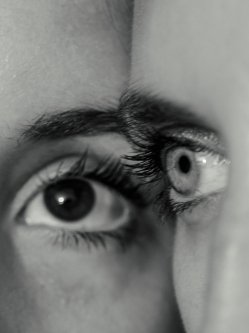 A close-up of a person's face showing one eye and part of the nose, with a reflection of an eye in the eye's cornea.