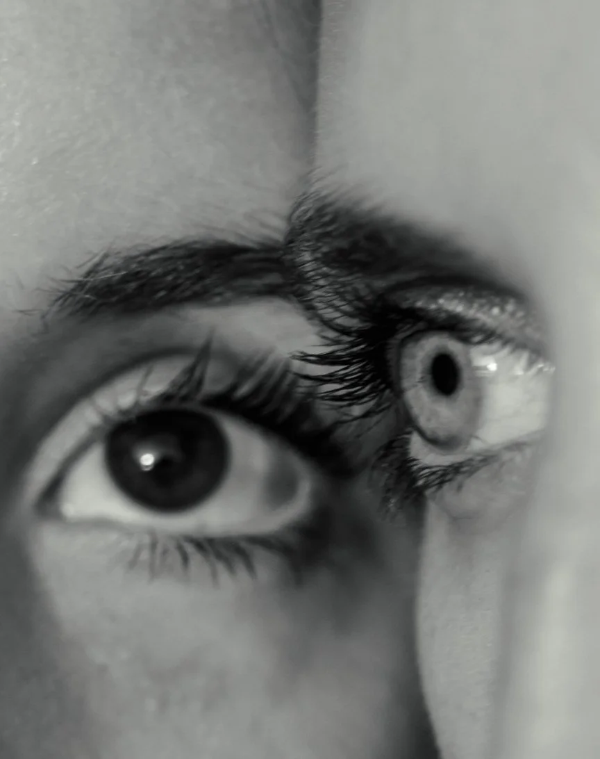 Close-up of a person's eyes in black and white, showing detailed eyelashes and eyebrows.