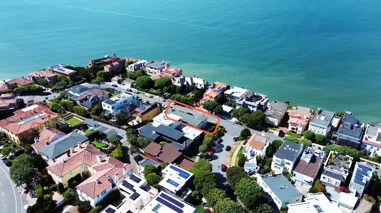 Aerial view of Sea Cliff neighborhood in San Francisco with houses and residential buildings, some with solar panels, next to the ocean. 201 Sea Cliff specific property is outlined in red.