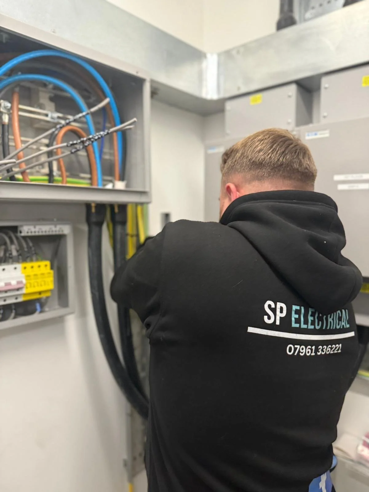     SP Electrical electrician working on wiring inside an industrial electrical panel.