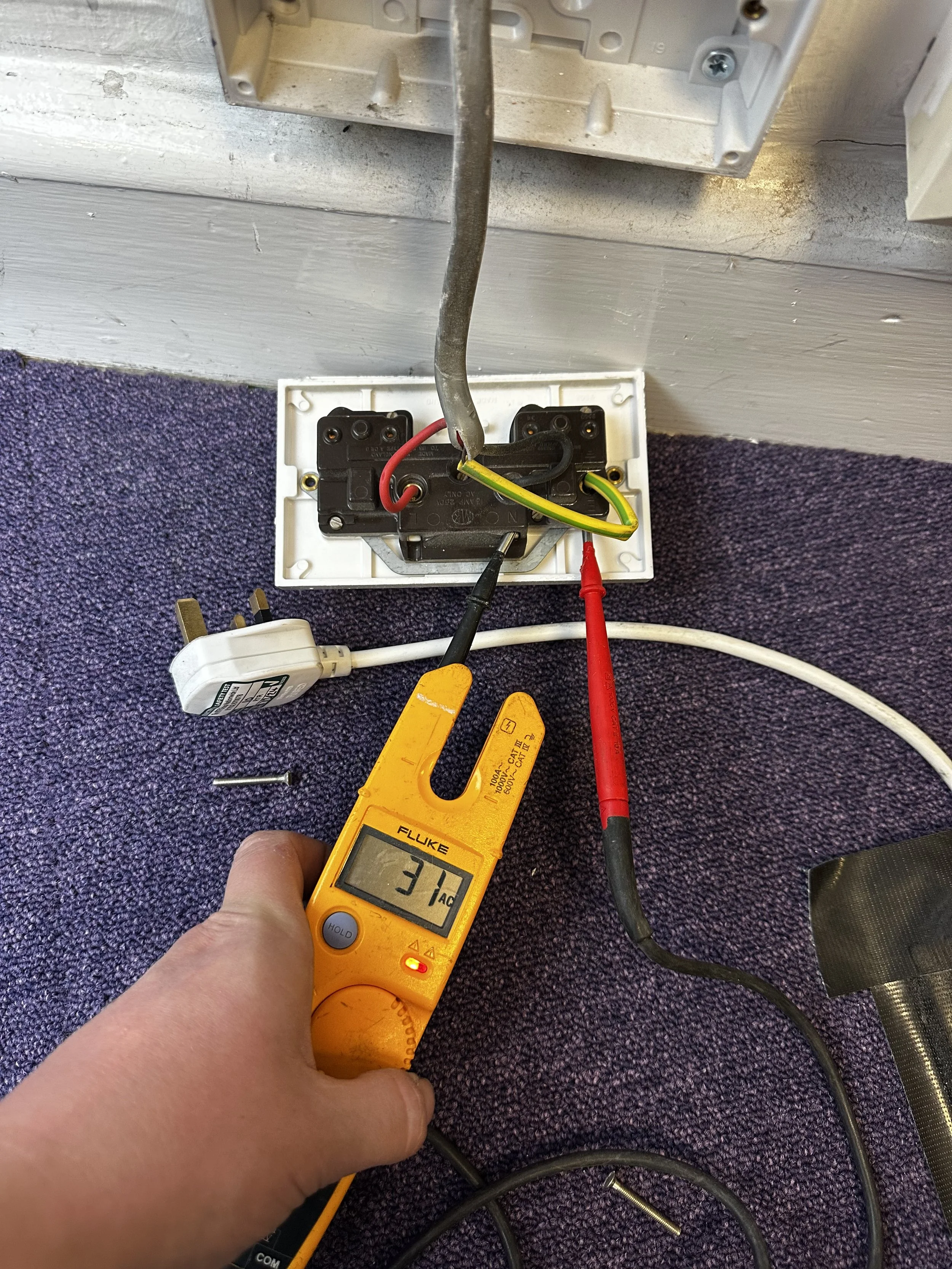 Electrical fault finding and voltage testing at a socket outlet.