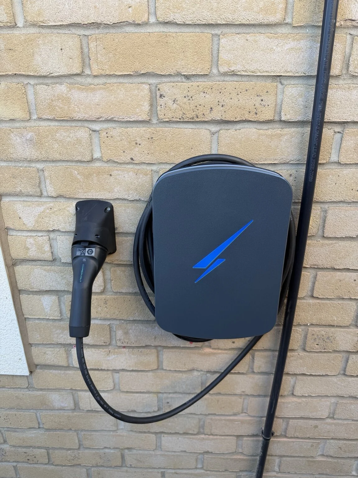 Hypervolt Home 3 Pro EV charger installed on an exterior brick wall at a residential property.