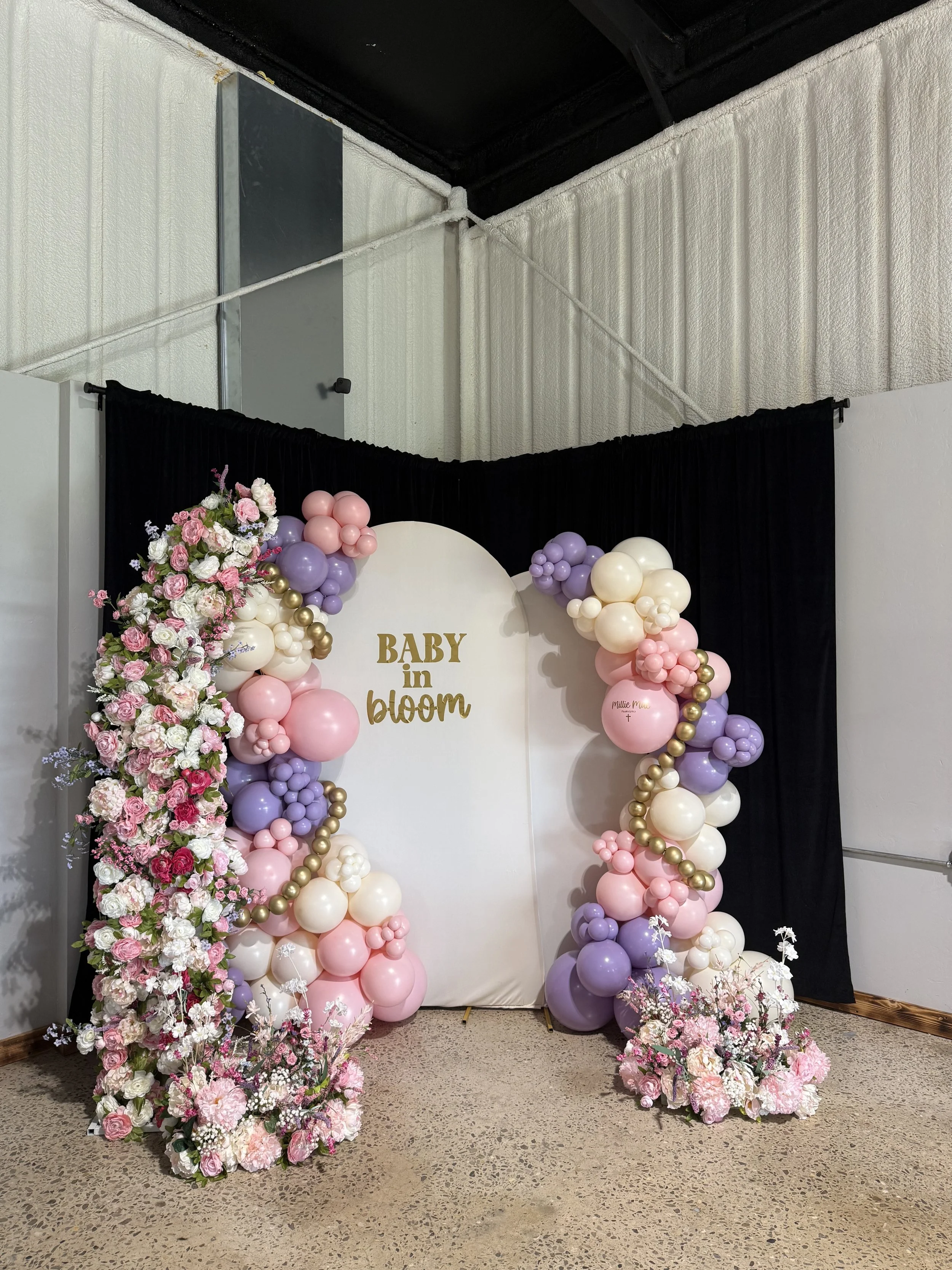 Decorative floral and balloon arrangement with a sign that reads 'Baby in bloom' at a baby shower or celebration event.
