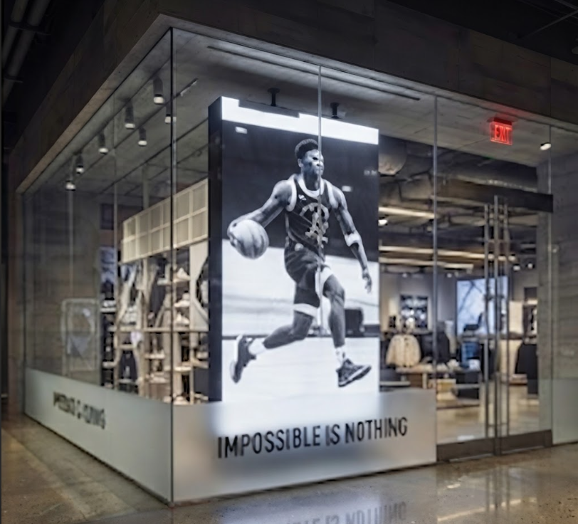 Large-scale athletic lifestyle graphic integrated into an open corner glass display layout.