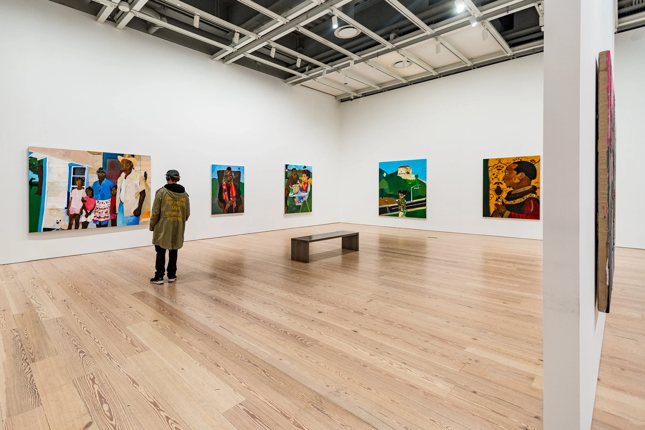 An art gallery with five colorful paintings on the white wall and two visitors observing the artwork.