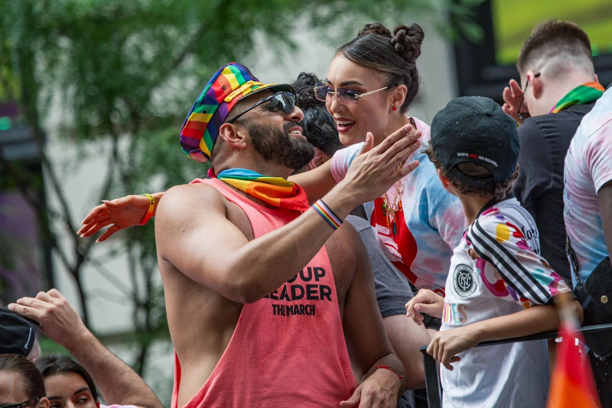 People celebrating at a Pride parade, wearing rainbow clothing and accessories.