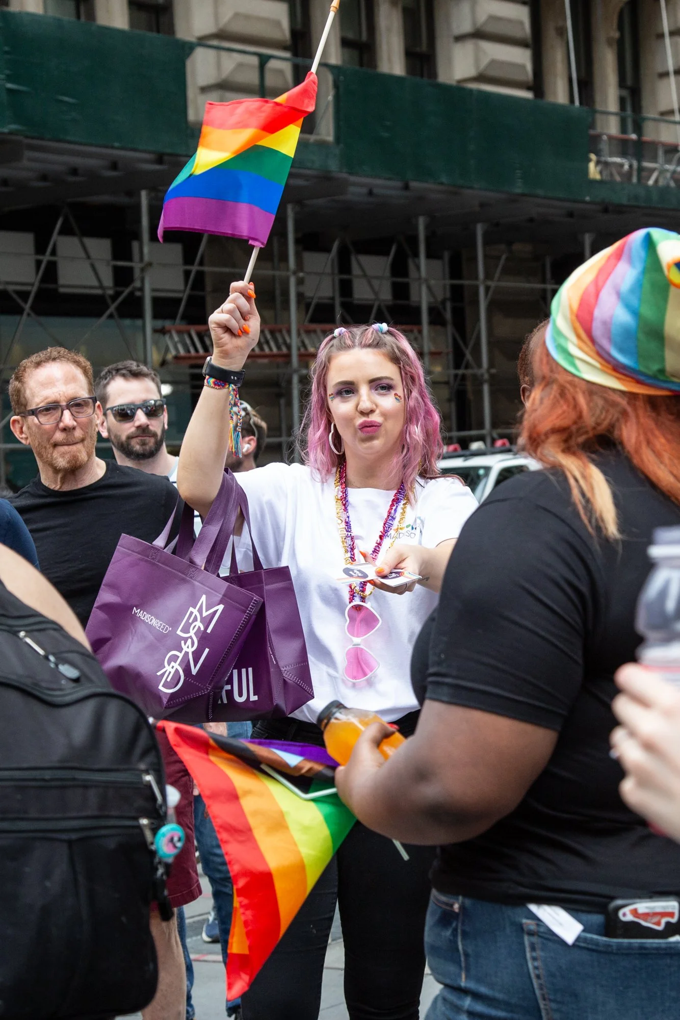 Crowd celebrating LGBTQ Pride with rainbow flags and a woman holding a small rainbow flag