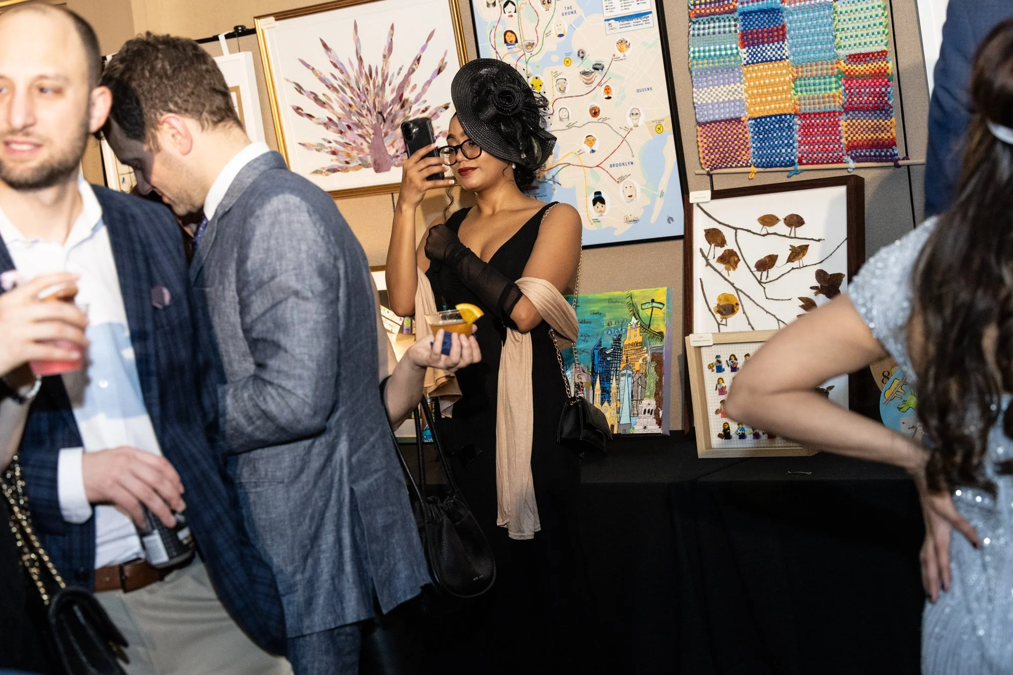 People attending an art exhibit featuring various colorful paintings and artwork displayed on the walls.