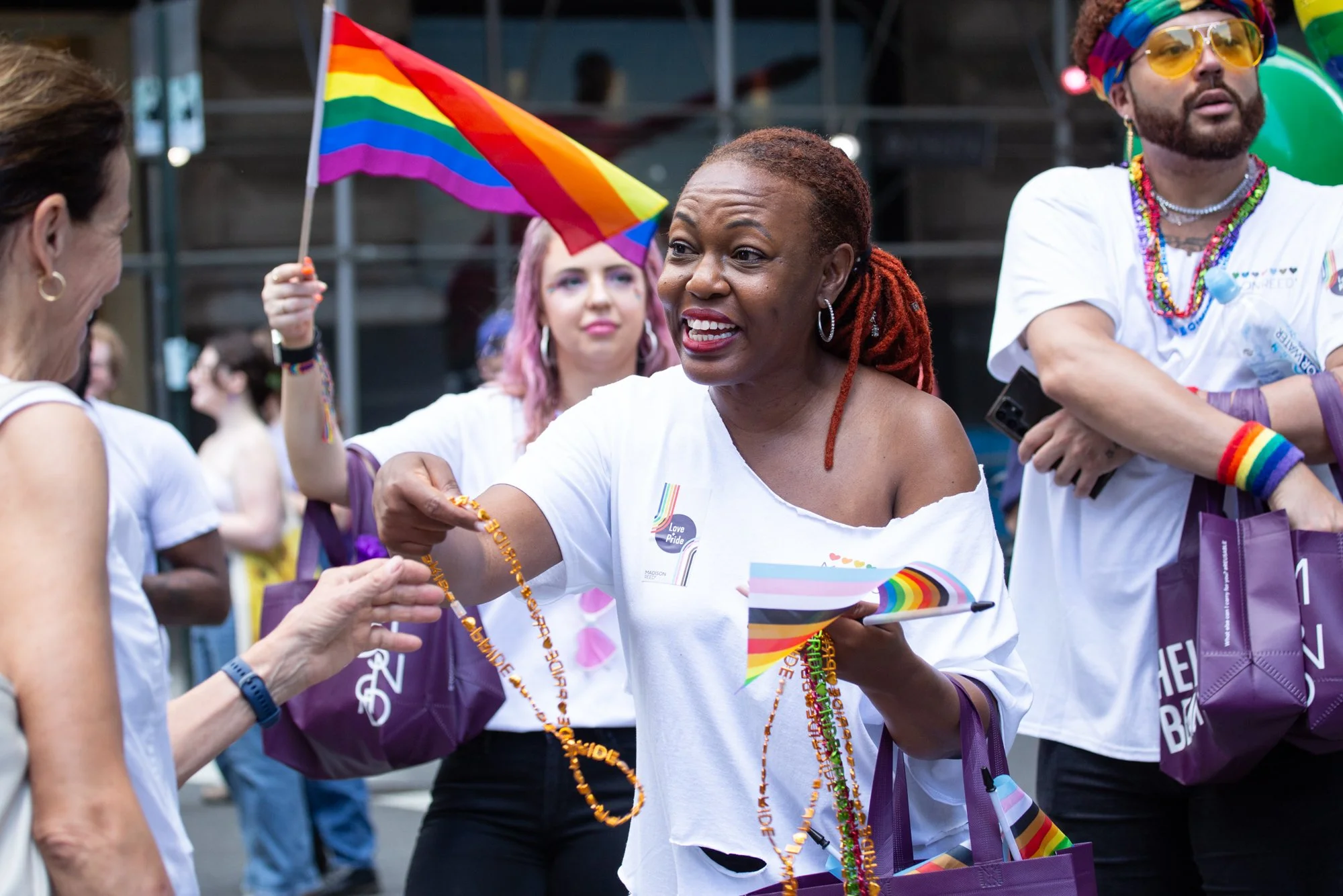 People celebrating at a Pride parade with rainbow flags and colorful LGBTQ+ accessories