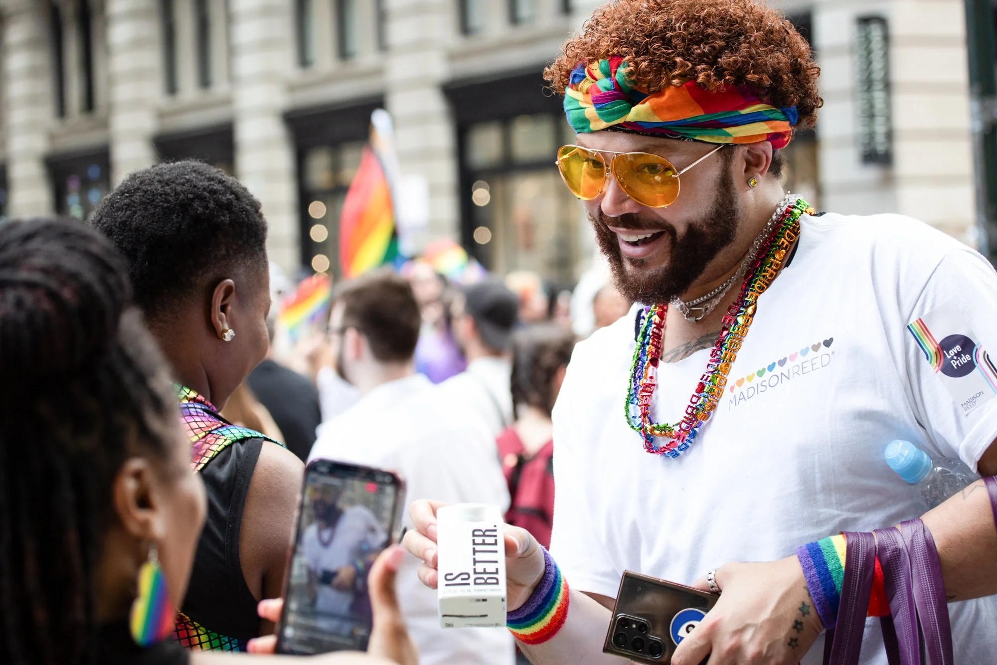 Man wearing rainbow accessories and Pride-themed clothing at a crowded LGBTQ+ Pride event