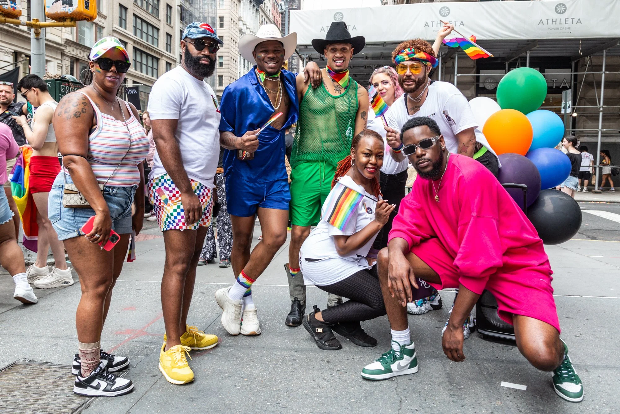 Diverse group celebrating at a Pride parade in New York City with rainbow flags, colorful clothing, and balloons