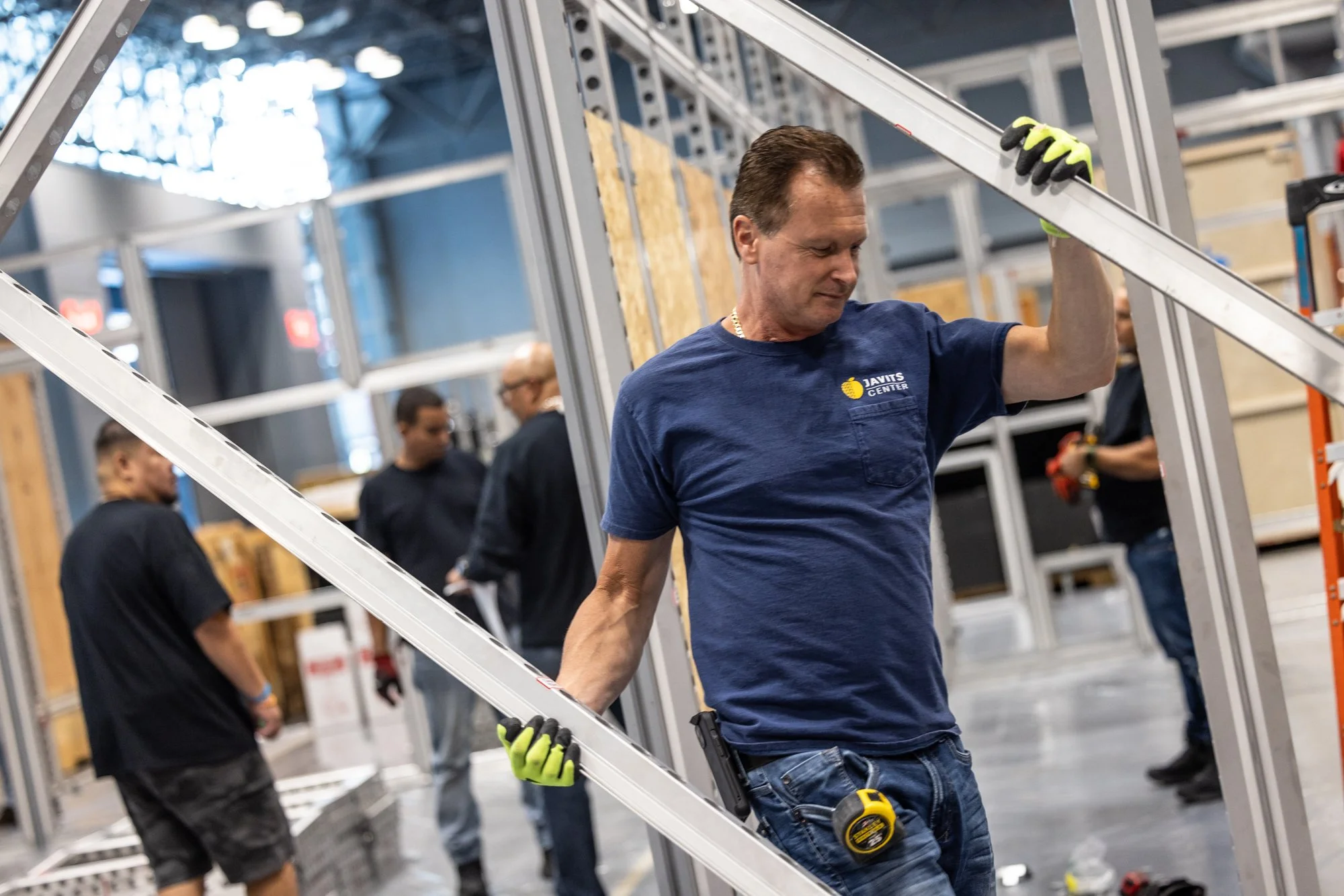 Construction worker in gloves carrying aluminum framing inside a building under renovation