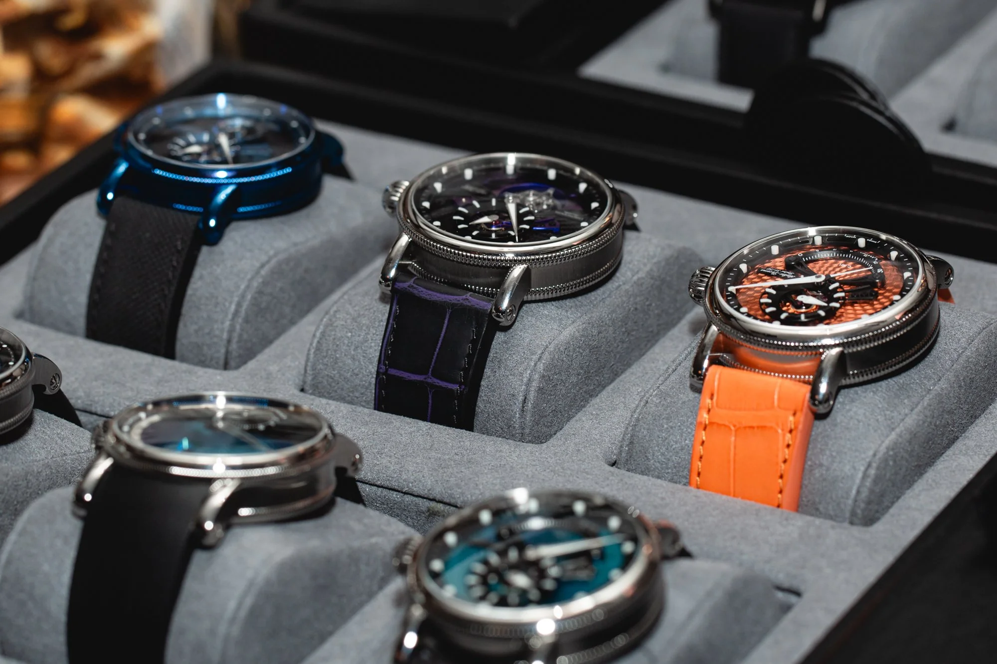 A display of luxury wristwatches with various designs and colors in a watch showcase case.
