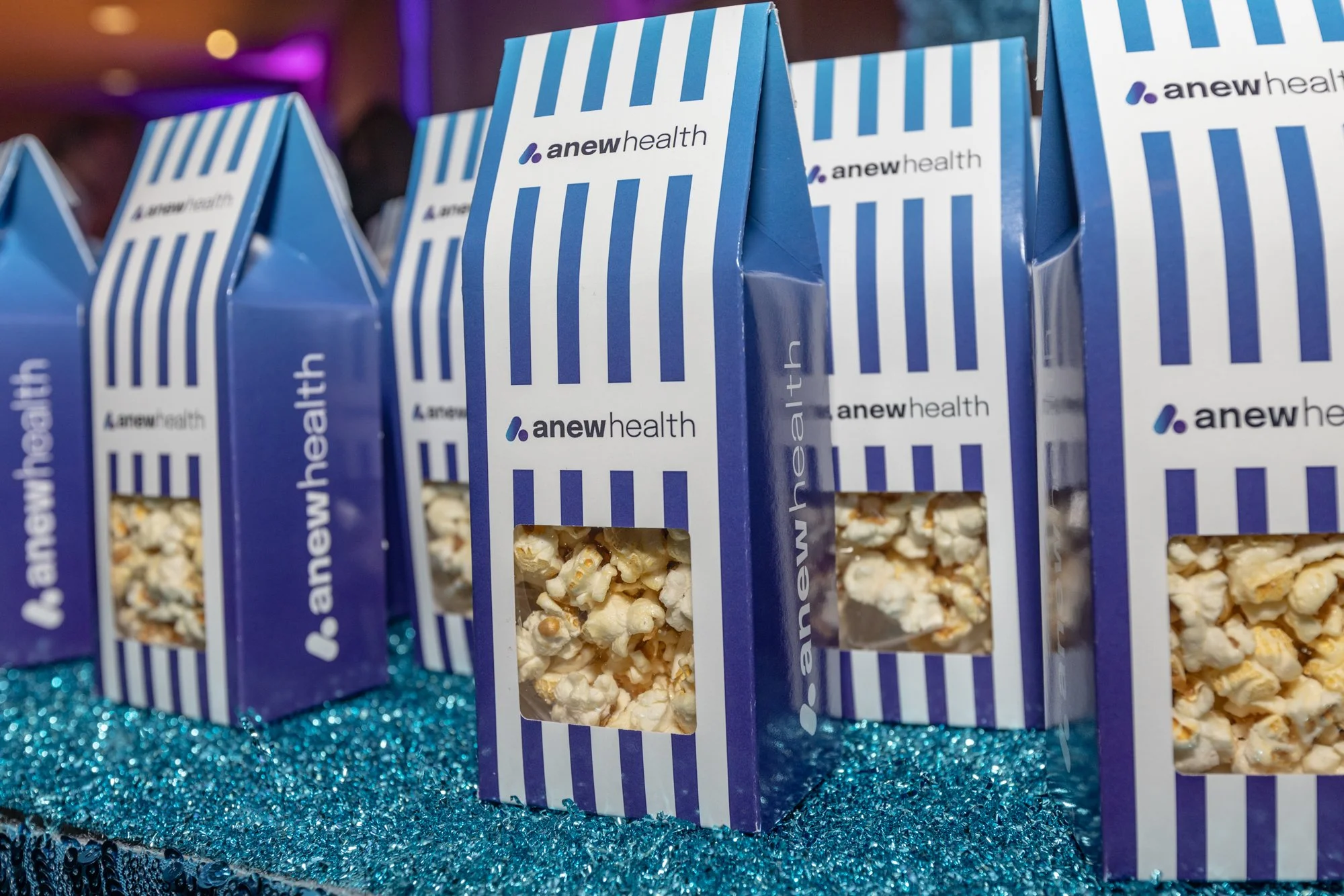 Blue and white striped boxes of popcorn with the label 'a new health' on a sparkling blue surface.
