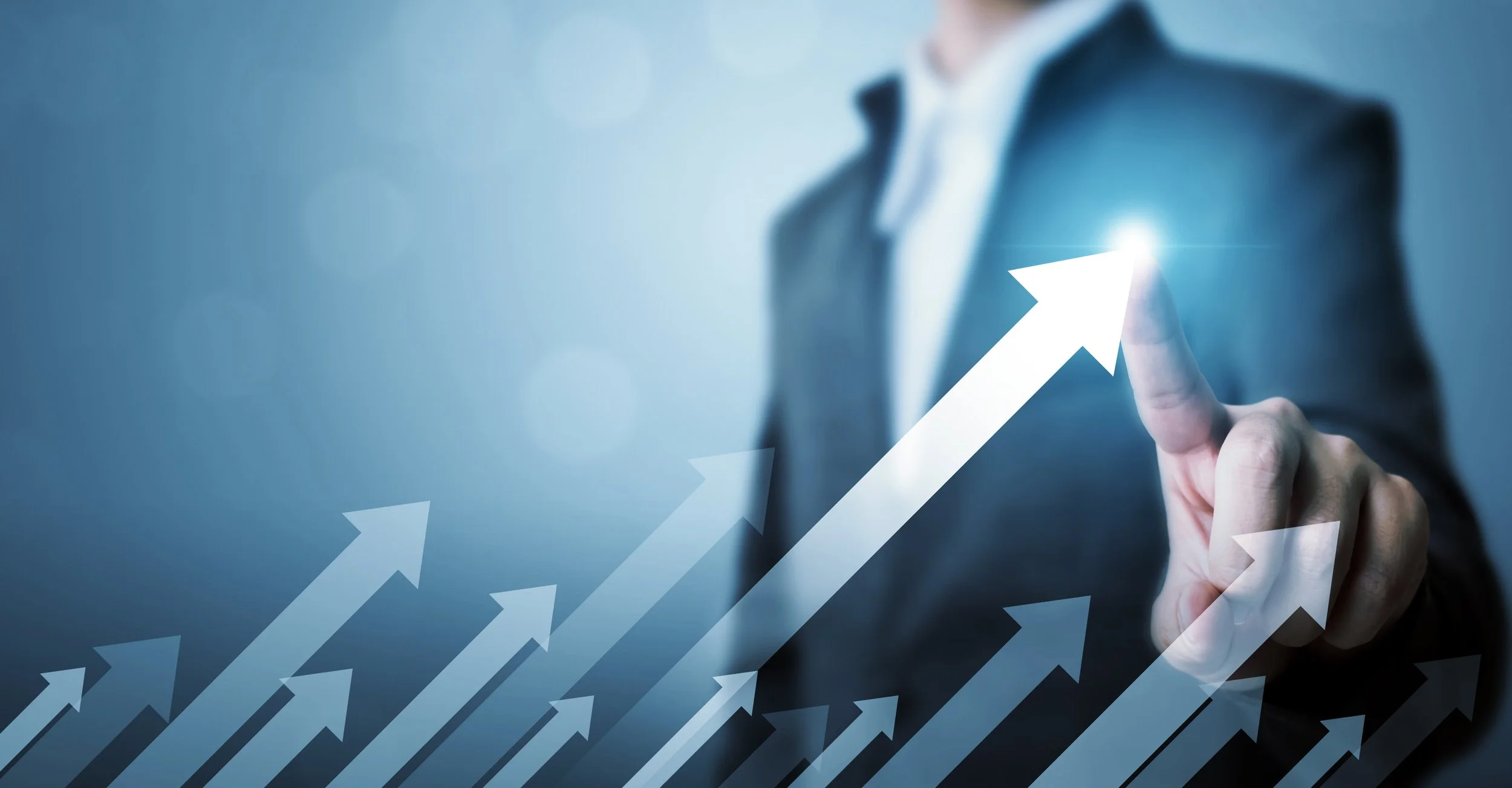 Person wearing a suit touching a glowing upward arrow with their finger, with other upward arrows in the background symbolizing growth or success.