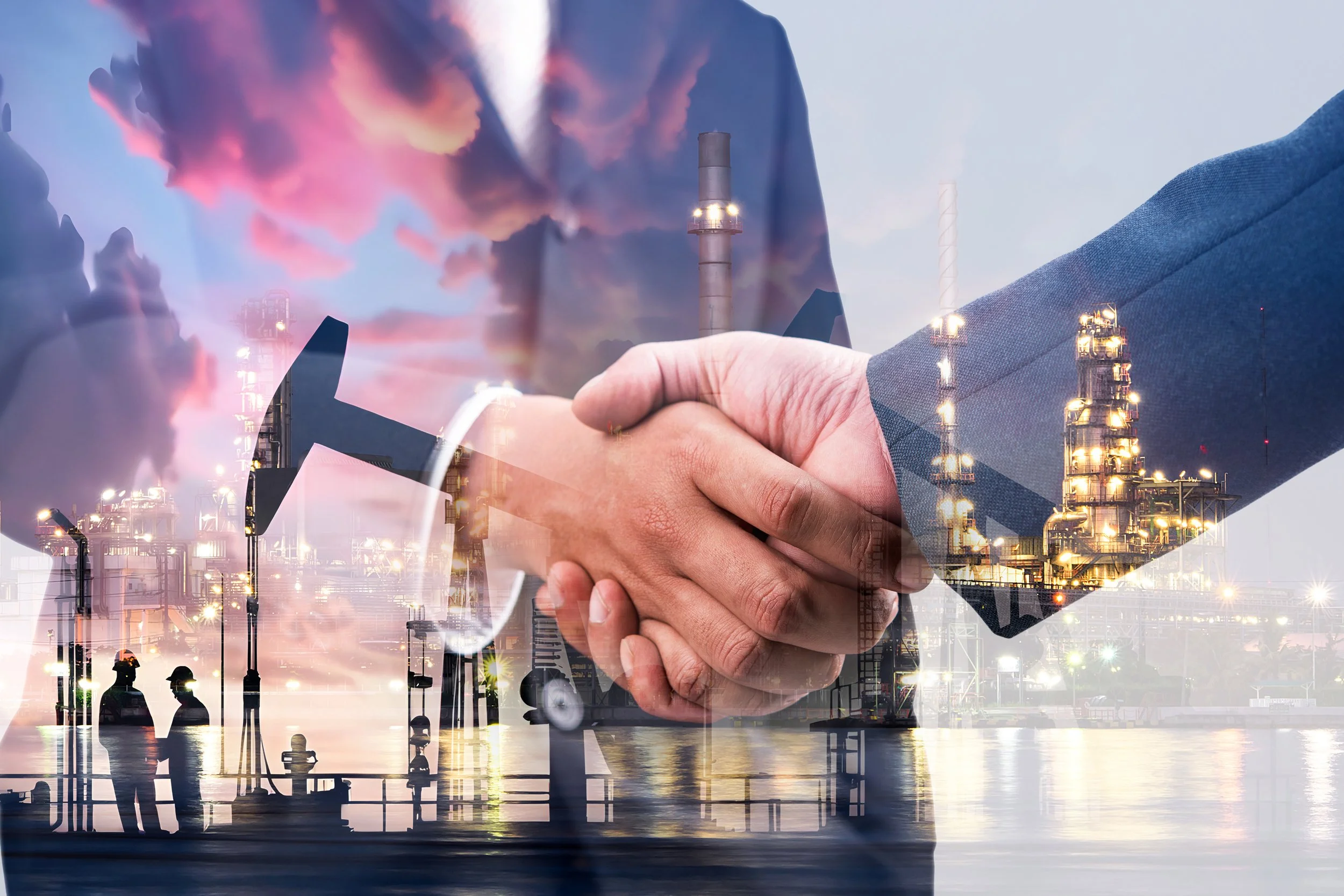 Double exposure of a business handshake over an industrial oil refinery with clouds and sunset.