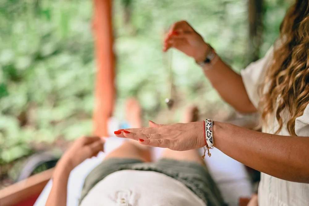 Person receiving a Reiki session outdoors with green foliage in the background. Become a Reiki Master at Synergy Healing Arts in Ogden. Utah.