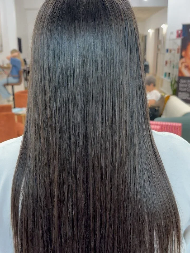 Close-up of a person's long, straight, shiny dark brown hair.