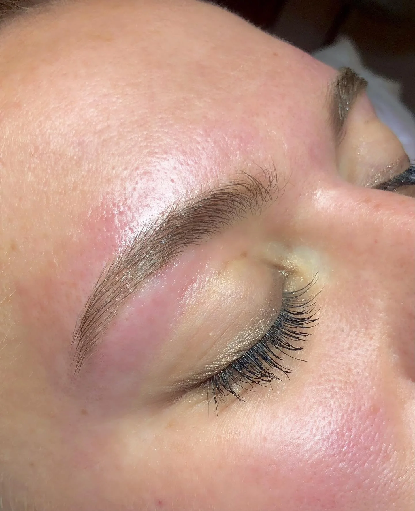 Close-up of a woman's face showing her closed eye, eyebrow, and skin texture.
