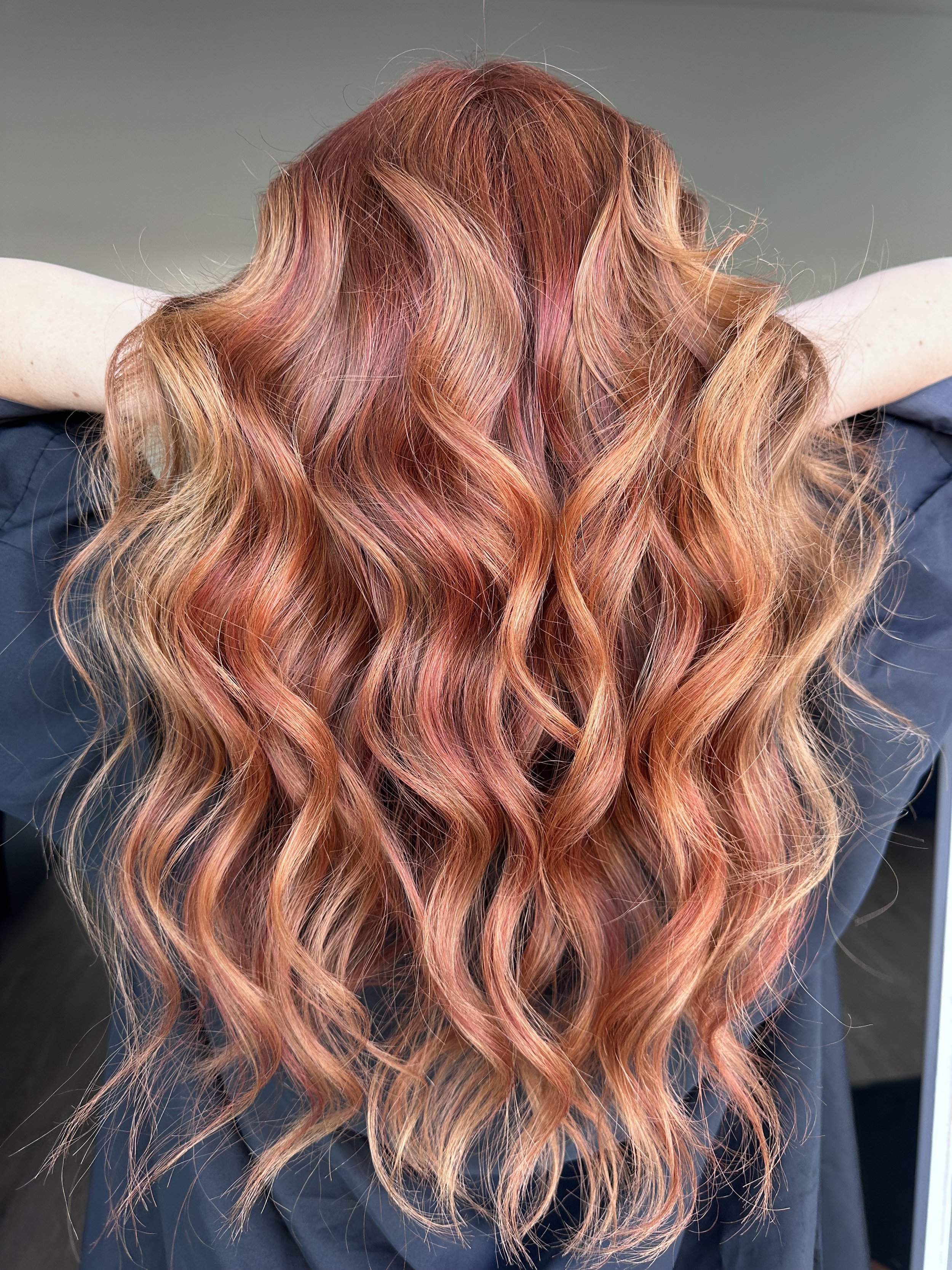 Back view of a person with long, wavy, reddish-orange hair.