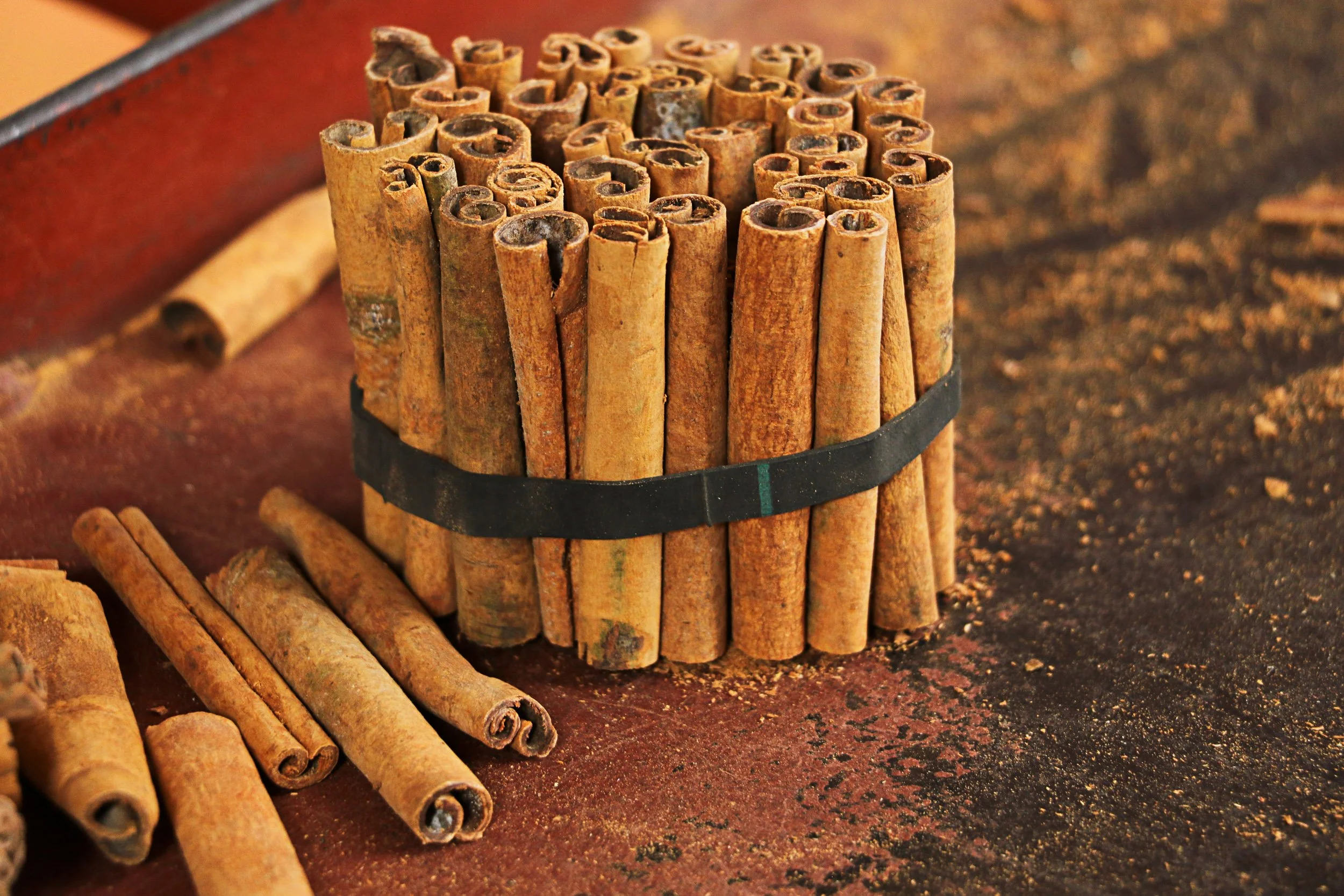 Bundled cinnamon quills tied for grading, with loose bark and ground spice around them