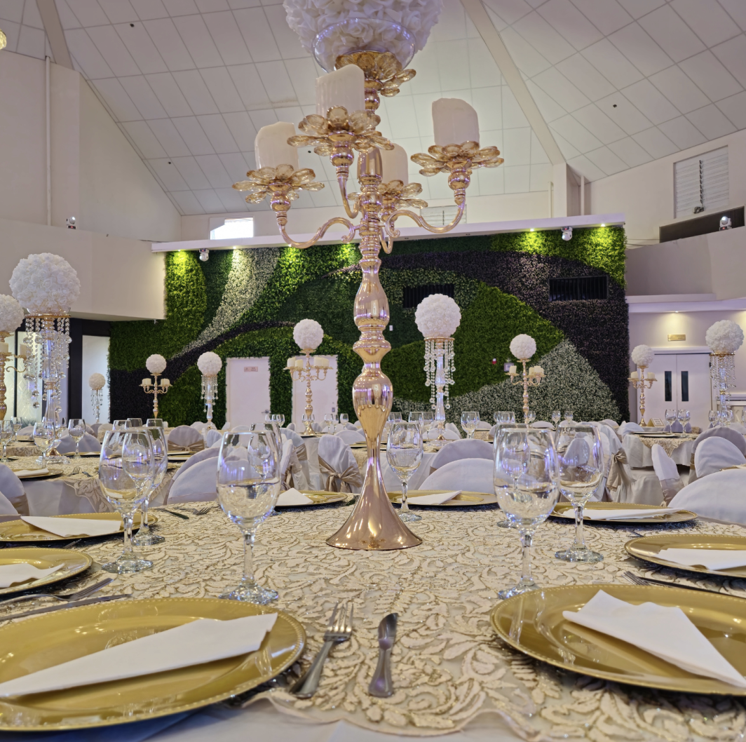 Elegant banquet table setup with gold place settings, tall centerpieces, and greenery at Crystal Palace Ballroom.