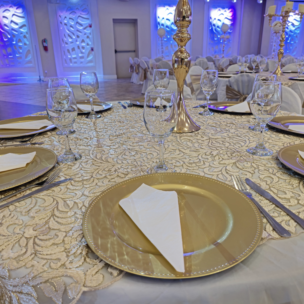 Formal table setting with gold charger plates, white linens, glassware, and elegant decor at Crystal Palace Ballroom.