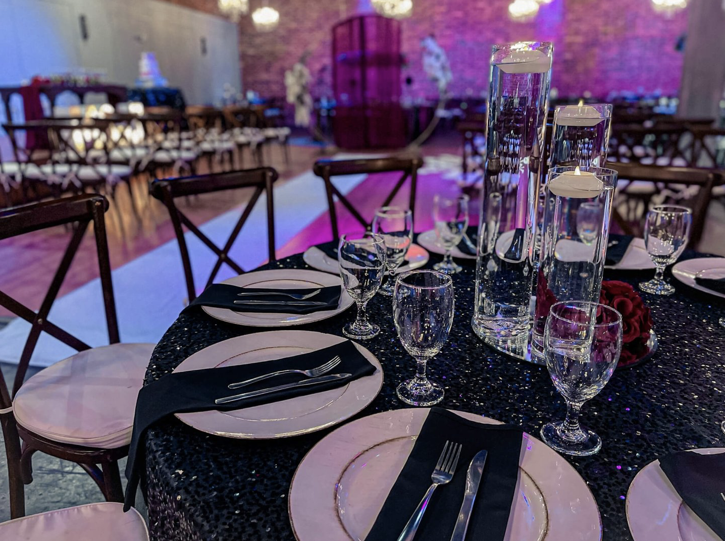 Formal reception table featuring black linens, black chairs, glassware, and elegant place settings.