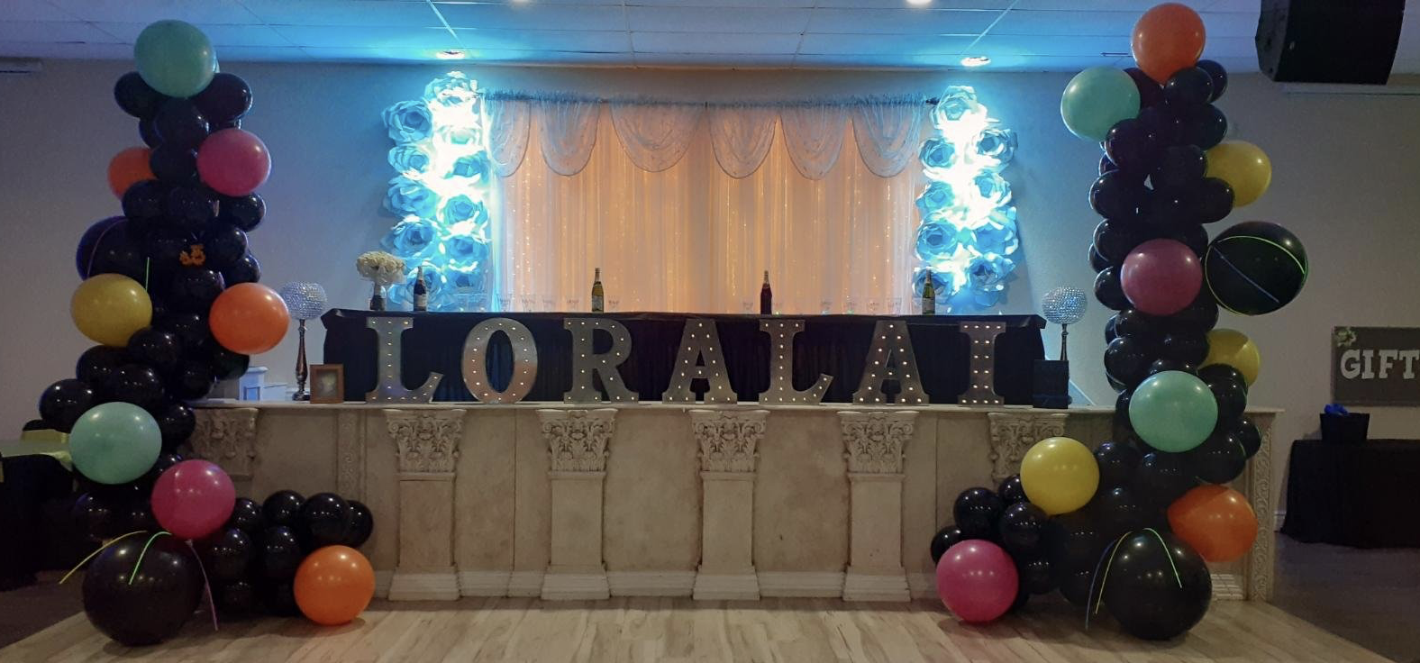 Decorated event display featuring illuminated letters, balloons, and blue accent lighting.