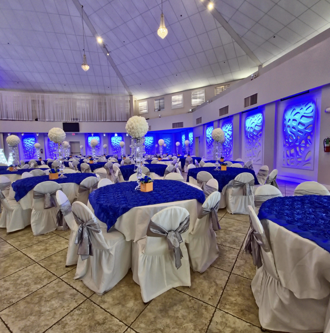Crystal Palace Ballroom decorated for a large celebration with round tables, white linens, and blue lighting.