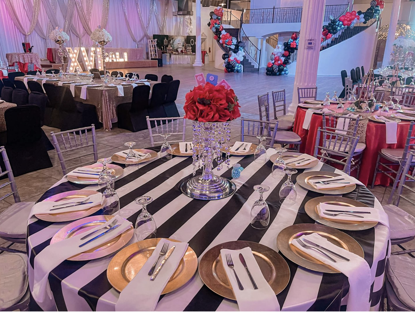 Formal table setting featuring black chairs, layered place settings, purple accents, and floral decor.