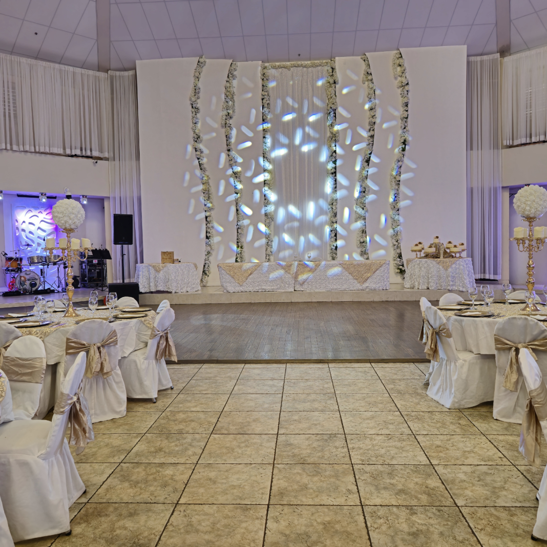 Elegant event setup at Crystal Palace Ballroom featuring white linens, gold accents, and a decorative backdrop.