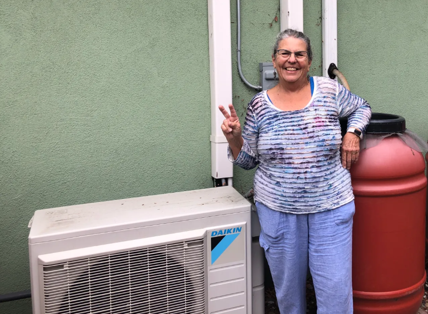 Petaluma resident Patricia Webb stands next to her heat pump mini-split outdoor condenser. (Natasha Juliana / For the Argus-Courier)