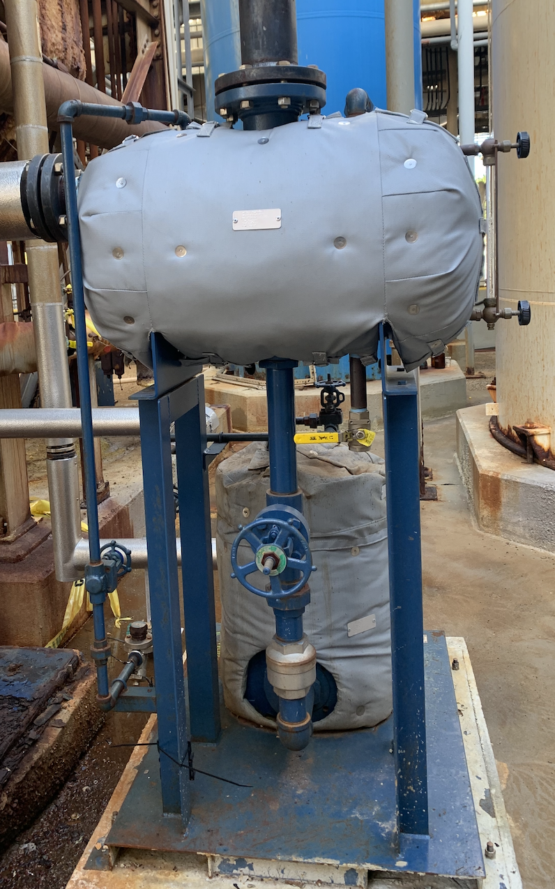 Industrial equipment with blue metal frame, pipes, and a large oval-shaped component covered in gray fabric.