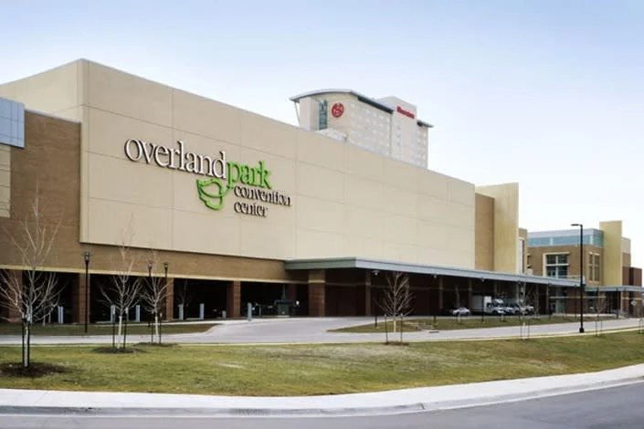 Exterior view of Overland Park Convention Center with a beige building, bare trees, and a clear sky.