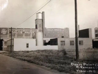 Original Davis factory with a sign that reads 'Davis Paint' in Kansas City, viewed from the street with a utility pole in the foreground.