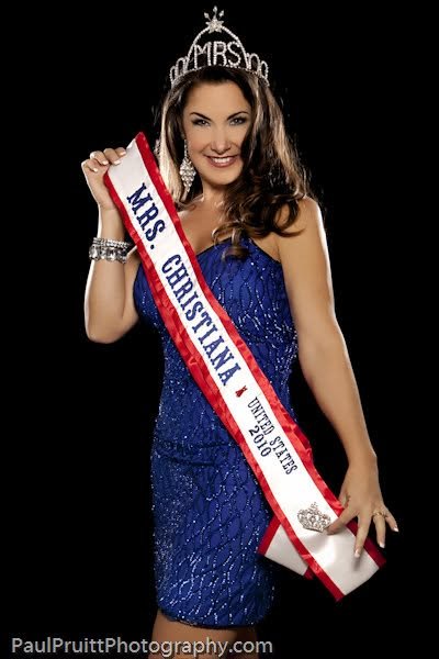 Woman wearing a tiara that says "Mrs." and a sash that reads "Mrs. Christina" from the United States, 2016, smiling and posing with a hand on her hip against a black background.