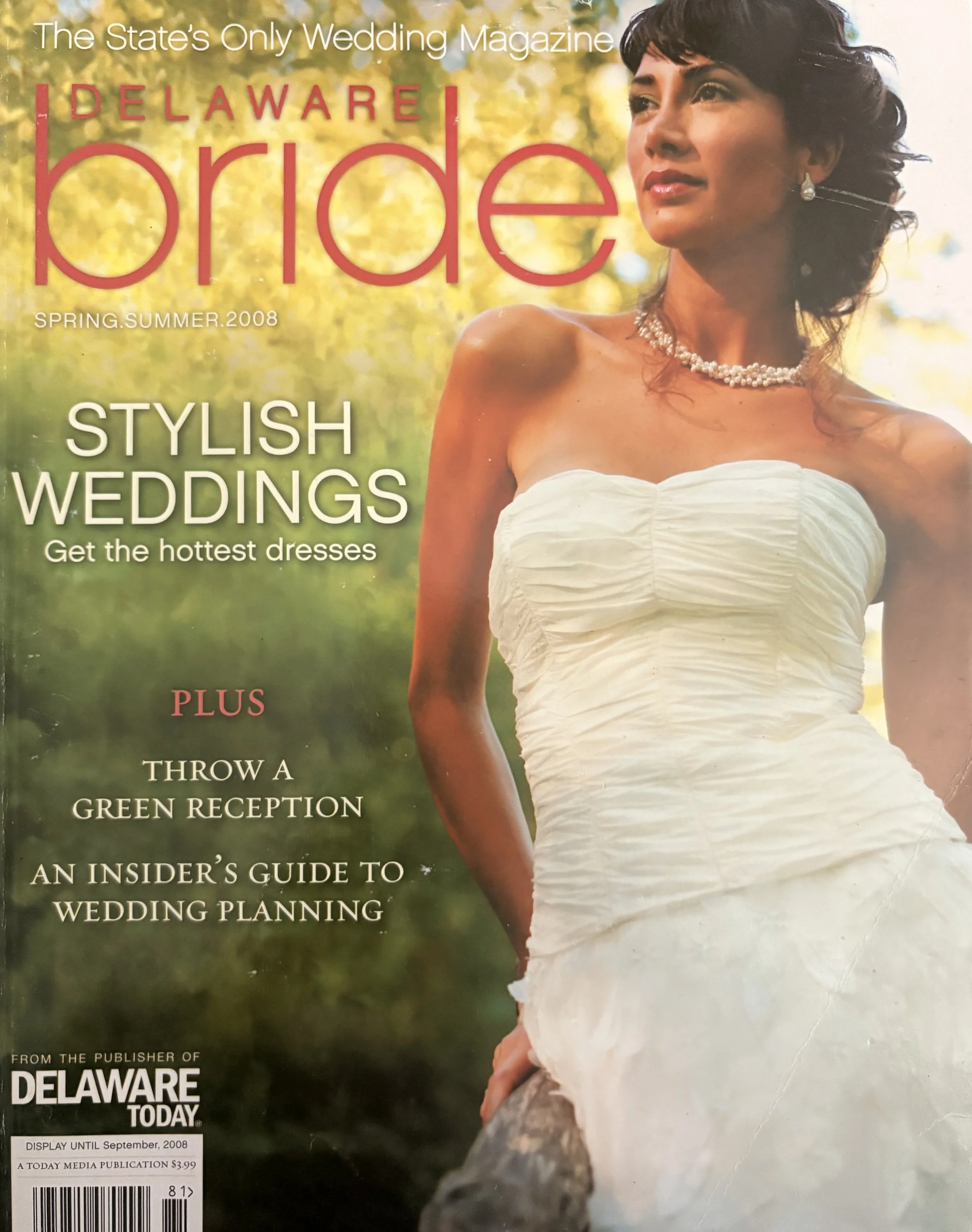 Cover of Delaware bride magazine featuring a woman in a strapless wedding dress, wearing pearl jewelry, overlooking a natural landscape with trees and sunlight.