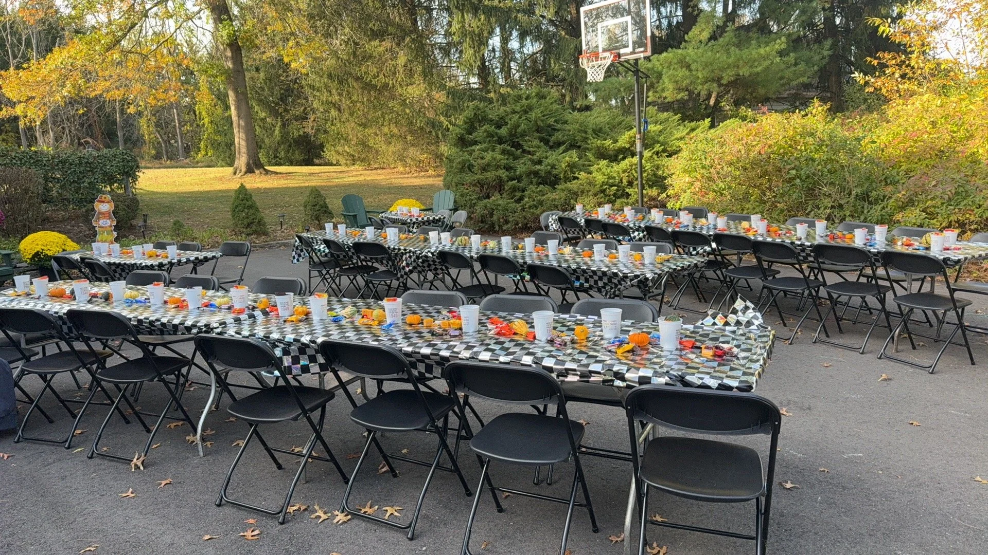 Outdoor group party tables set with black-and-white tablecloths and autumn decorations.