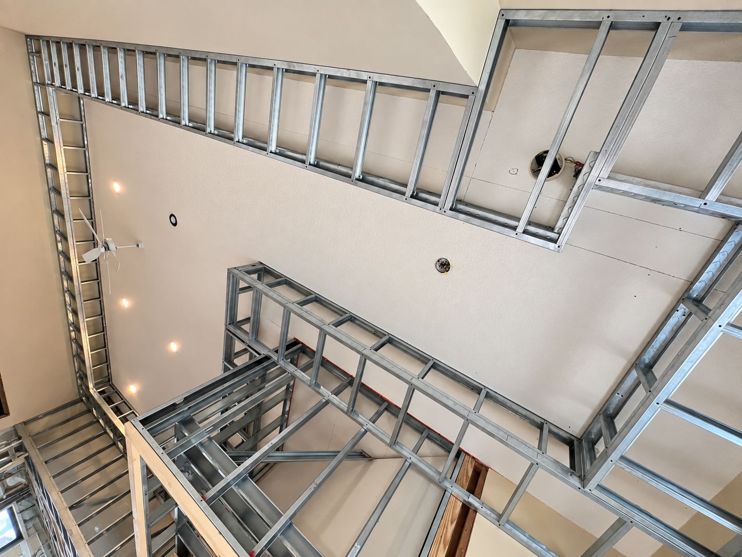 Metal framing structure in a building under construction, with drywall and lighting installed.