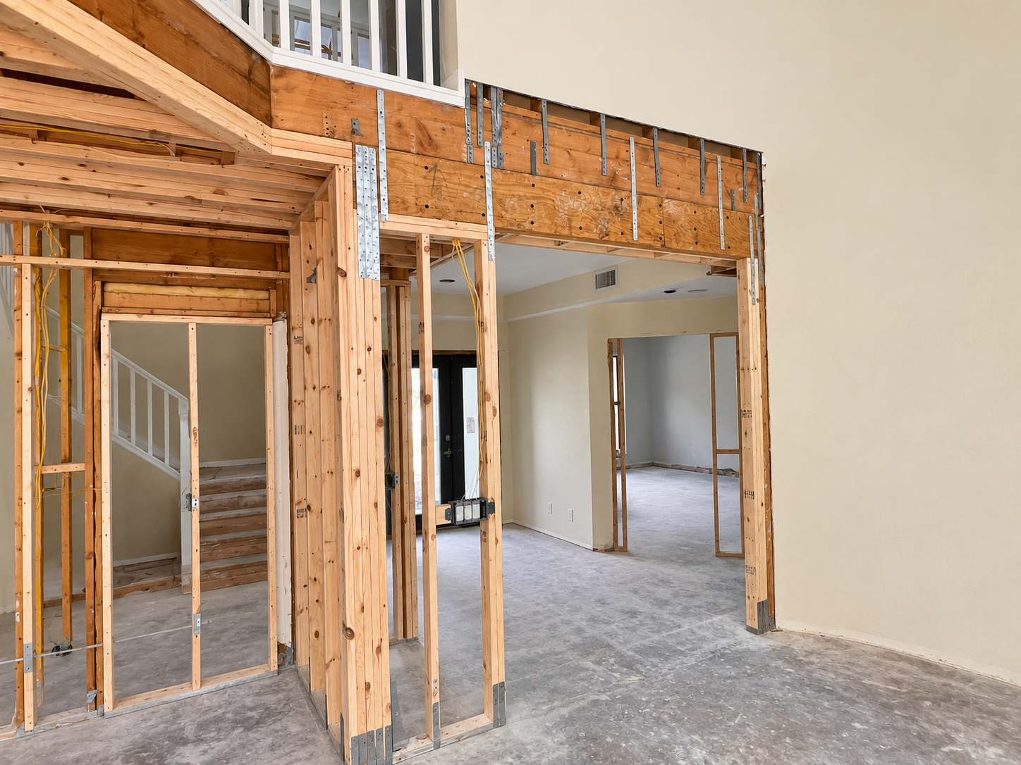 Interior view of a house under construction with exposed wooden framing and unfinished walls.