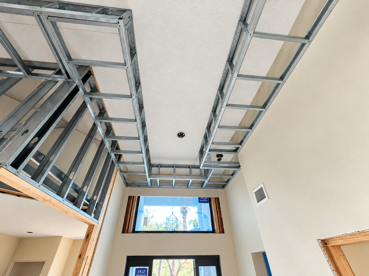 Construction site with metal framing for a ceiling and walls, showing an unfinished interior space during renovation.