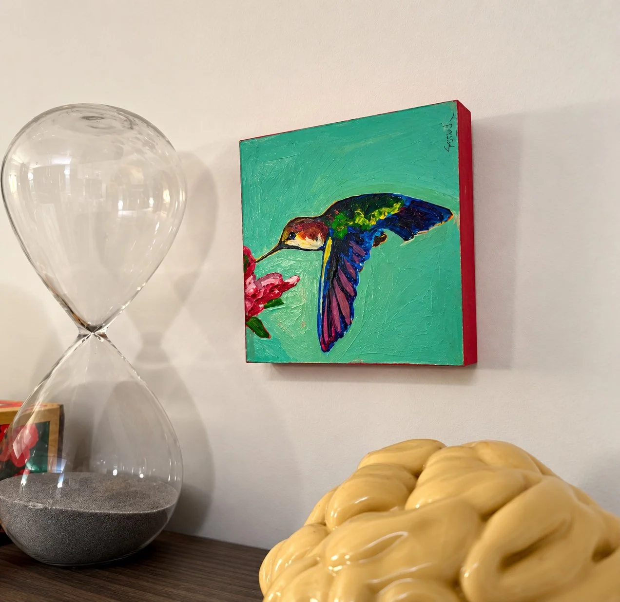 Hummingbird painting beside an hourglass