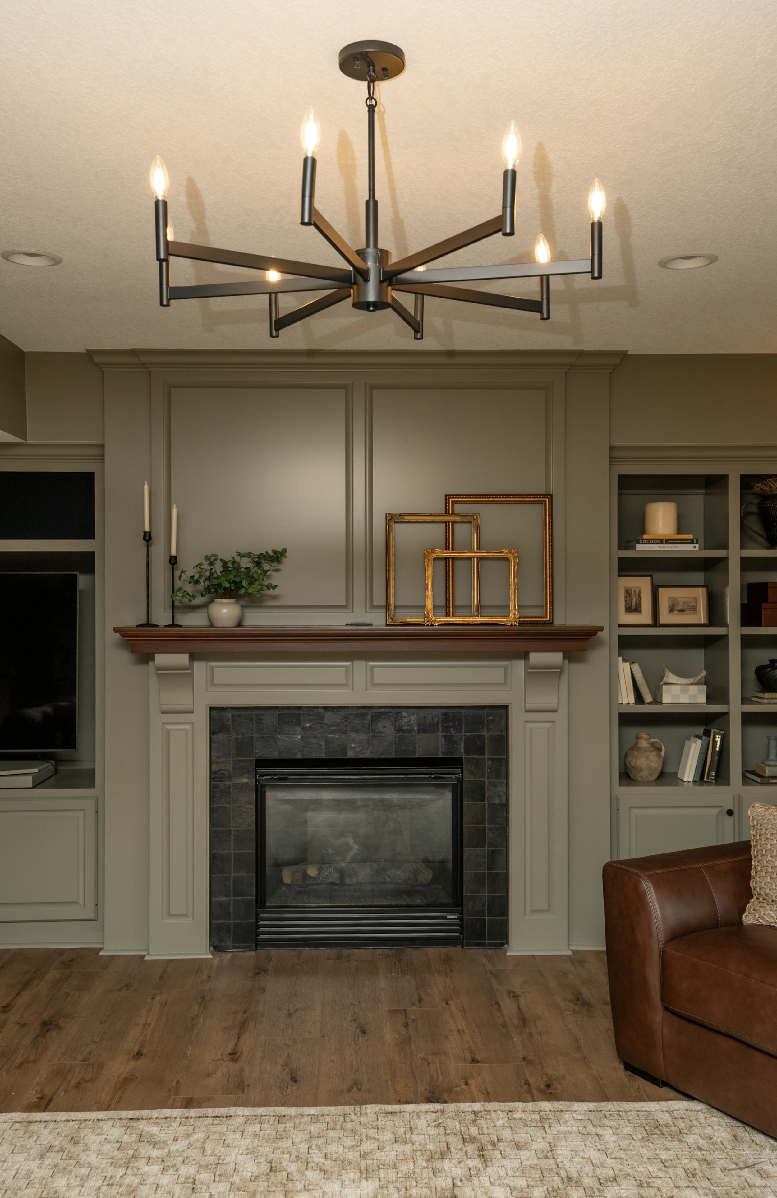 Living room with fireplace, built-in shelves, and modern chandelier.