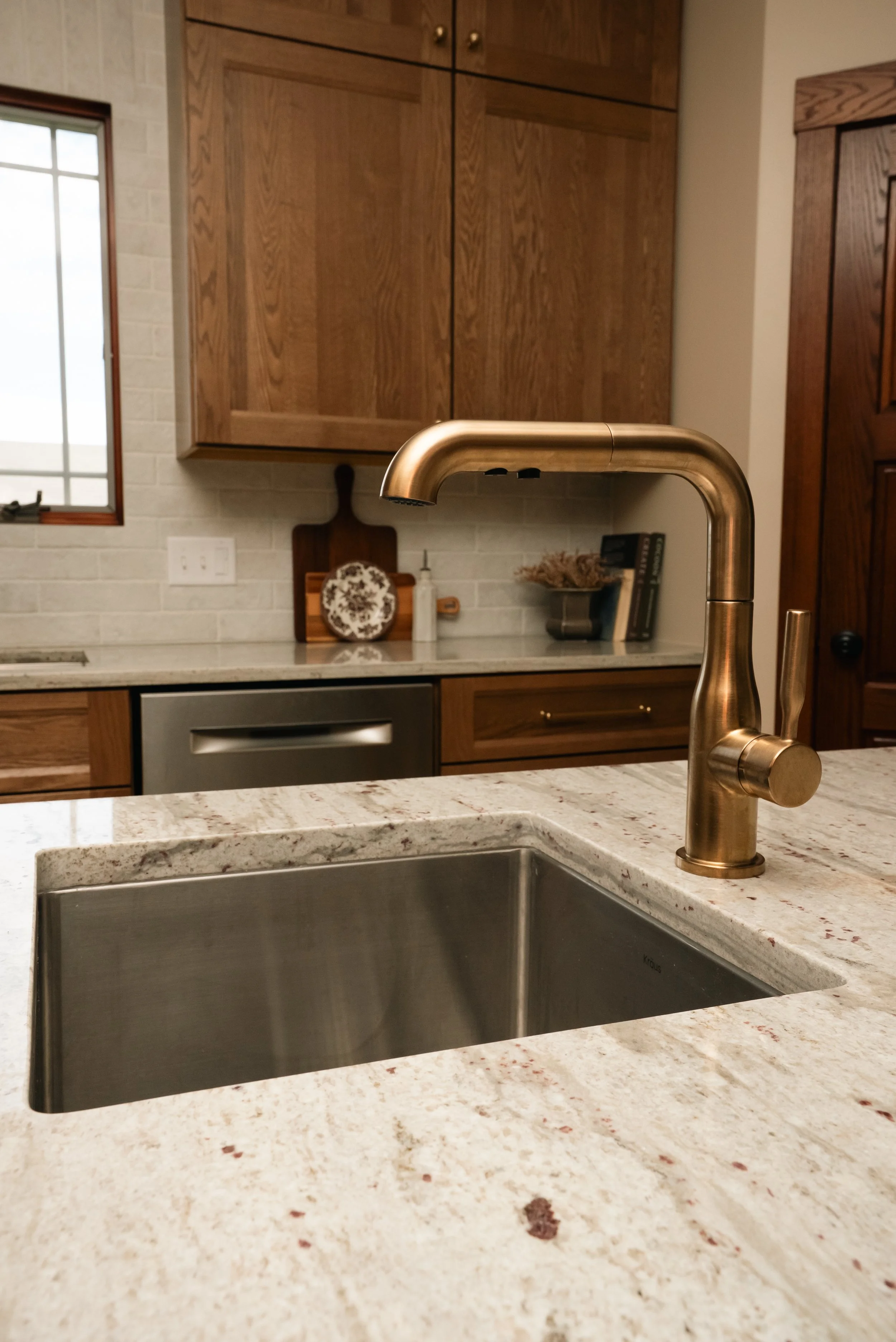 Transitional kitchen with champagne bronze faucet and white oak cabinetry. 