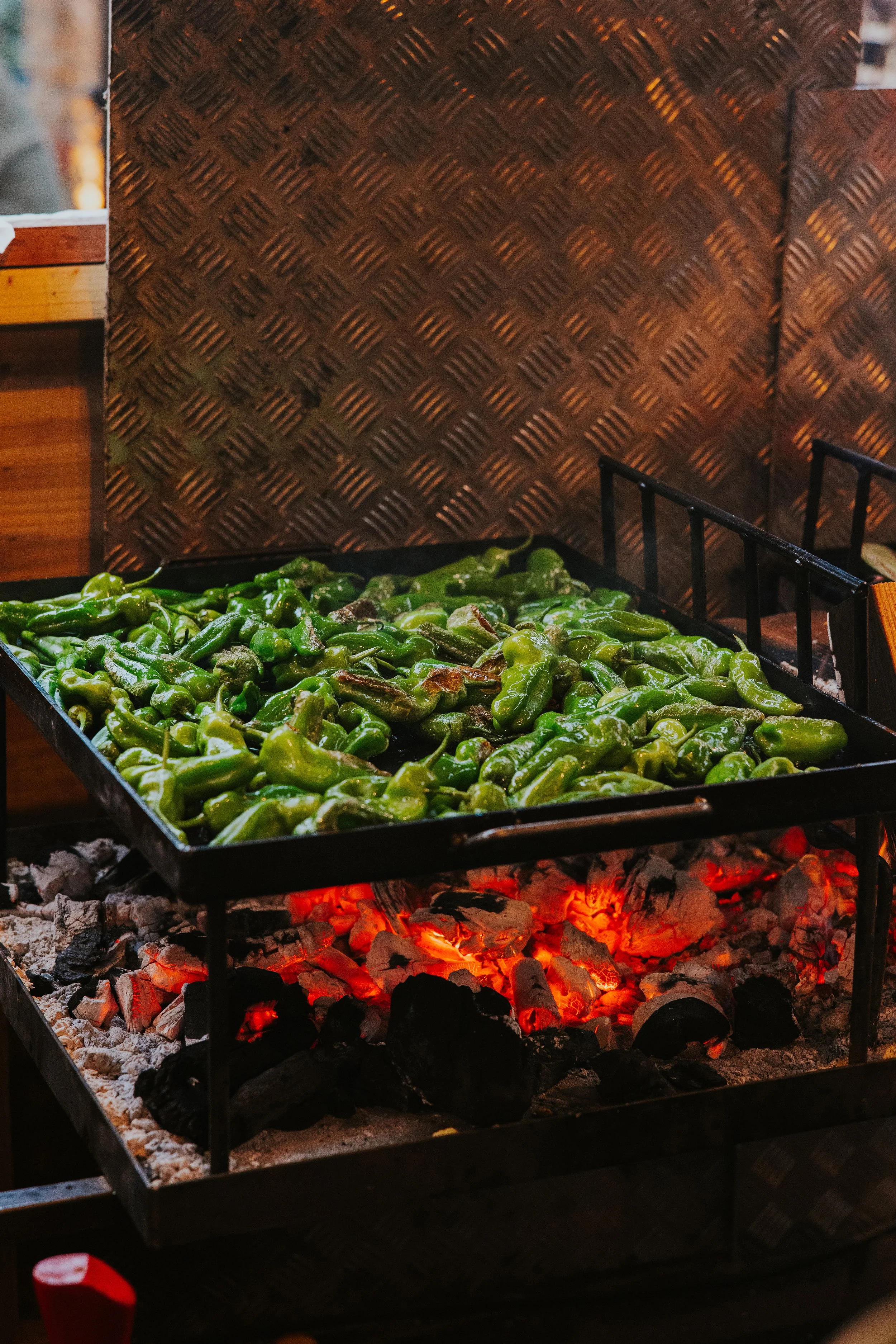 Padron peppers cooking over open fire coals, outdoor dining event - Josh Ward Creative