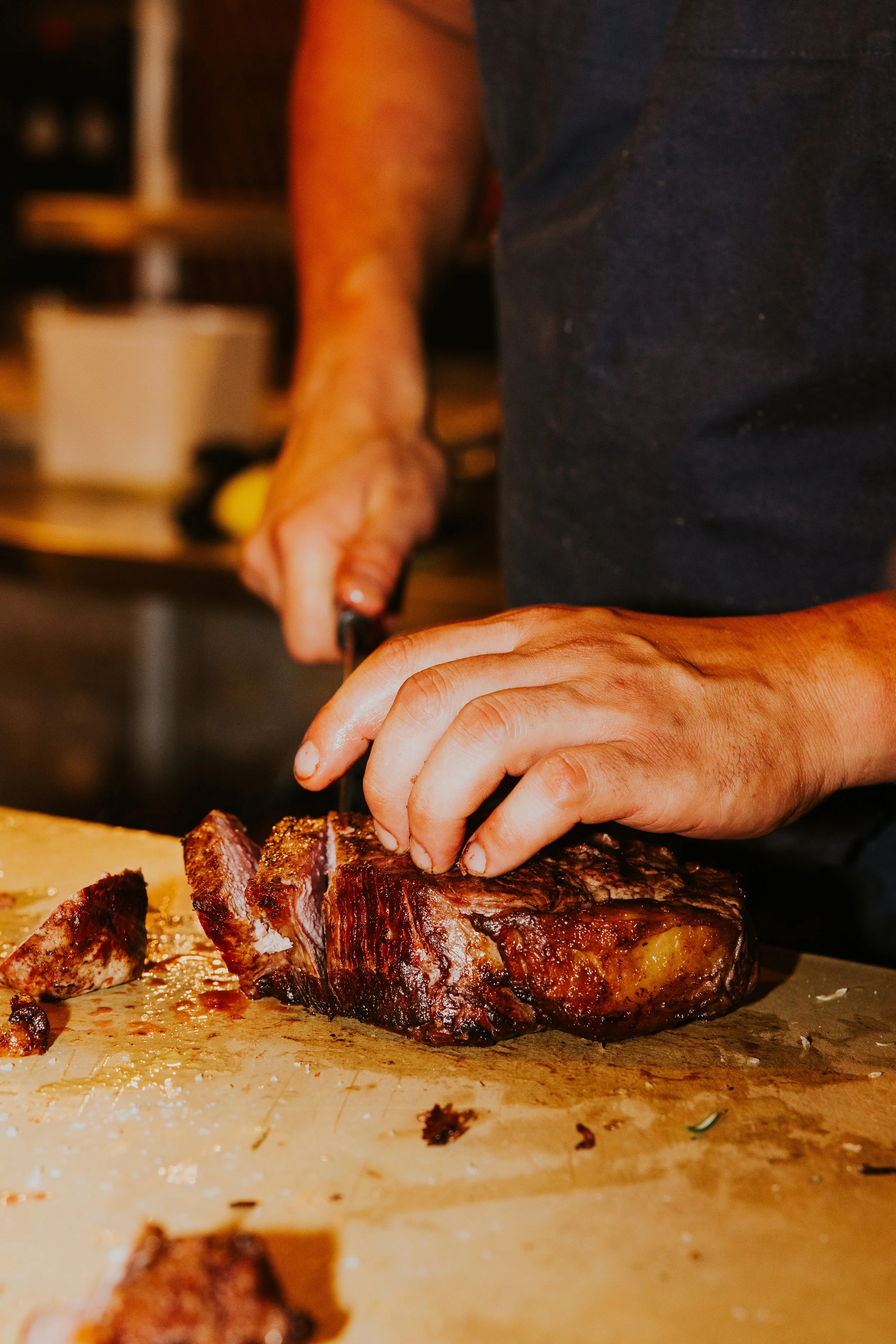 Chef slicing resting steak on cutting board, commercial culinary shoot - Josh Ward Creative