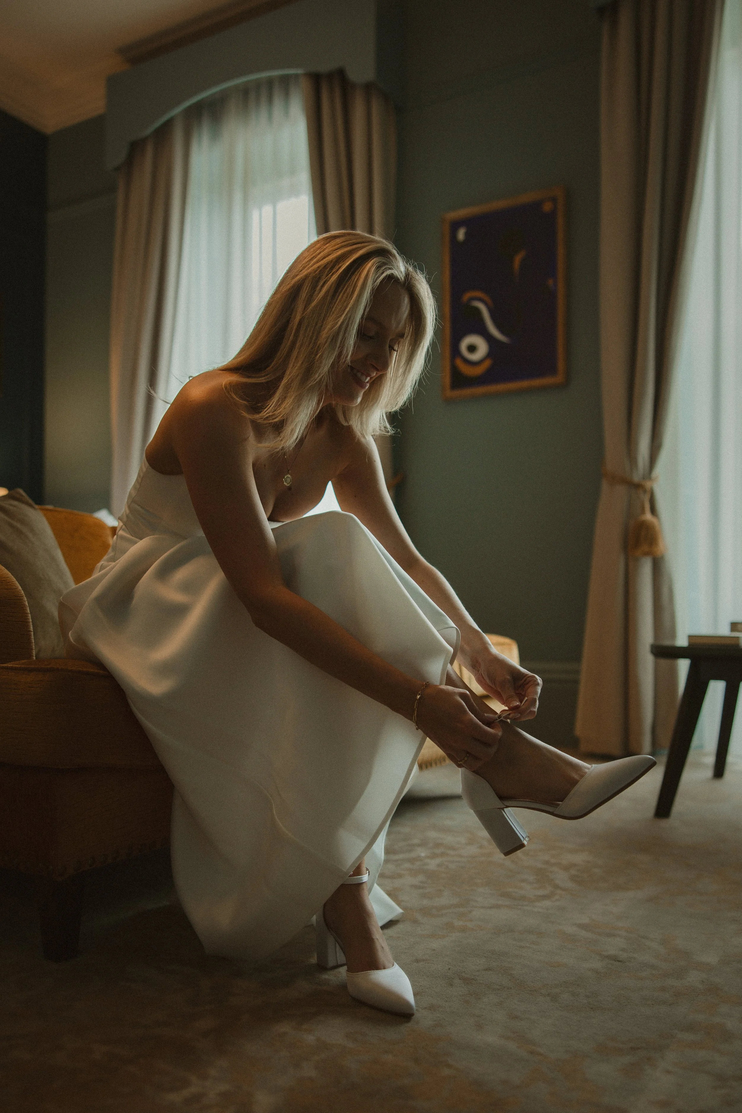 Bride putting on wedding shoes by natural window light - Josh Ward Creative