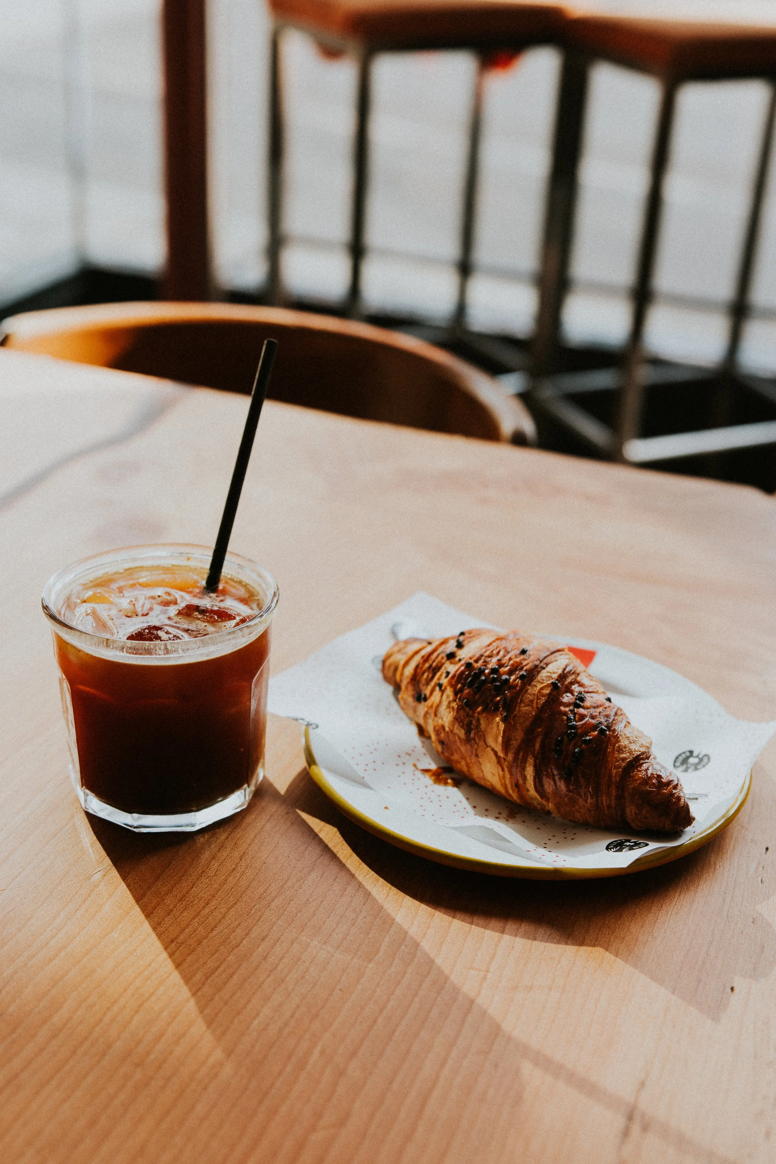 Iced coffee and fresh croissant on wooden cafe table, Cornwall - Josh Ward Creative